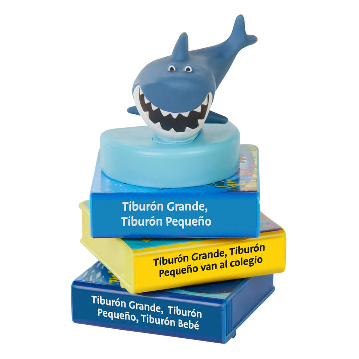 Pila de tres libros con una figura de tiburón encima sobre un fondo blanco.