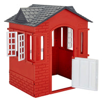 A red plastic playhouse with a dark gray shingled roof, white window frames, and a white door panel that is swung open, shown on a plain white background.