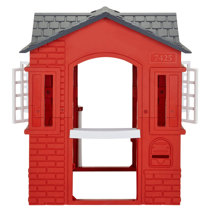A red plastic playhouse with a dark gray shingled roof, white shutters, and a back mail slot, shown on a plain white background.