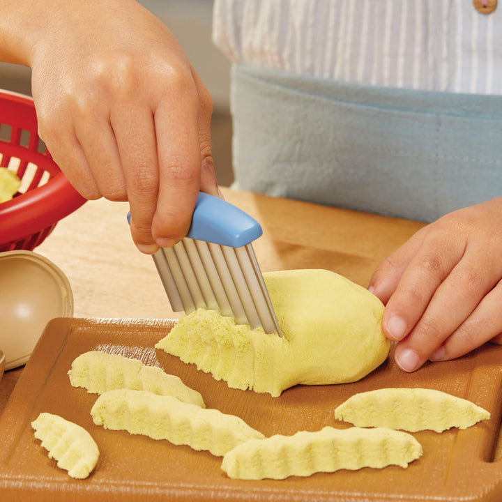 Child using a vegetable peeler to slice a sand potato 