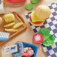 Play food set with hamburger, fries, and ground beef on a checkered tablecloth.