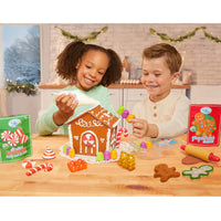 Two children playing with a gingerbread house kit