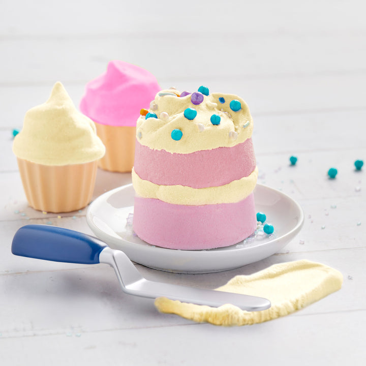 Pastel-colored cake with a spatula and colorful sprinkles on a light background