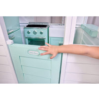 Child's hand on a Sea Foam green door with a oval Little Tikes Logo. Also showing Sea Foam green oven and sink inside a playhouse