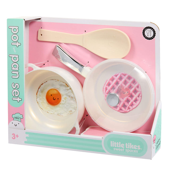 Toy cookware set in retail packaging, featuring a white toy frying pan with a clear lid, a beige toy spoon, and a pot, labeled 'pot pan set' and 'little likes sweet spaces'.