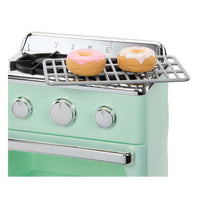 Two small donuts sitting on rack on top of the oven shown on a white background