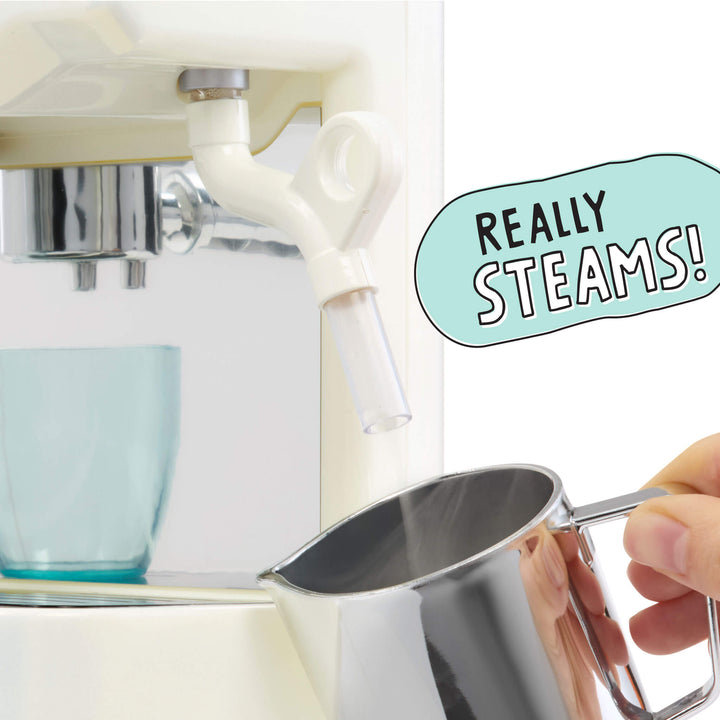 A close-up of a white espresso machine dispensing steam into a  pitcher held by a hand. A light blue speech-bubble graphic reads 'REALLY STEAMS!'.