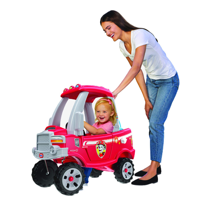 Child sitting in the fire truck with a  parent standing next to it
