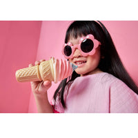 Girl wearing pink, flower sunglasses, a pink shirt and holding a play ice cream cone against a pink background.