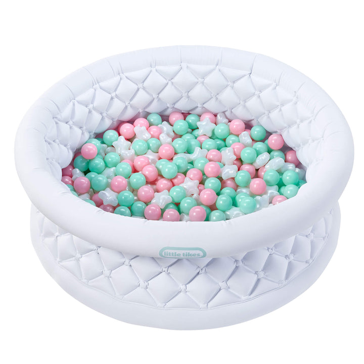 A white inflatable ball pit with a quilted diamond pattern, filled with pastel pink and mint green plastic balls, on a solid white background.