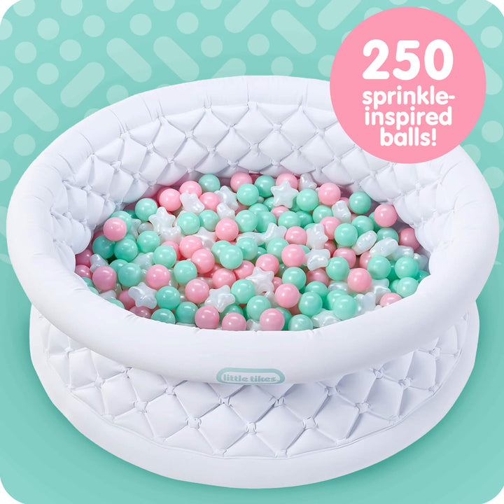 An inflatable white ball pit pool with a quilted diamond pattern, filled with pastel pink, mint green, and white plastic balls. A pink circular badge in the top right reads '250 sprinkle-inspired balls!'.