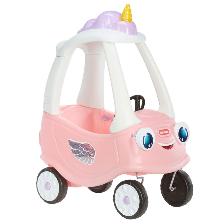 A pink and white plastic ride-on toy car with a unicorn horn on top, featuring a smiling face on the front and a wing sticker on the side.
