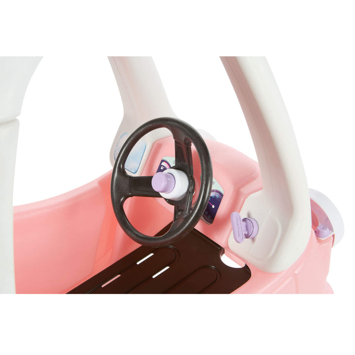 Close-up of a children's toy car interior with a pink body, white steering column, black steering wheel, and small purple accents on a white background.