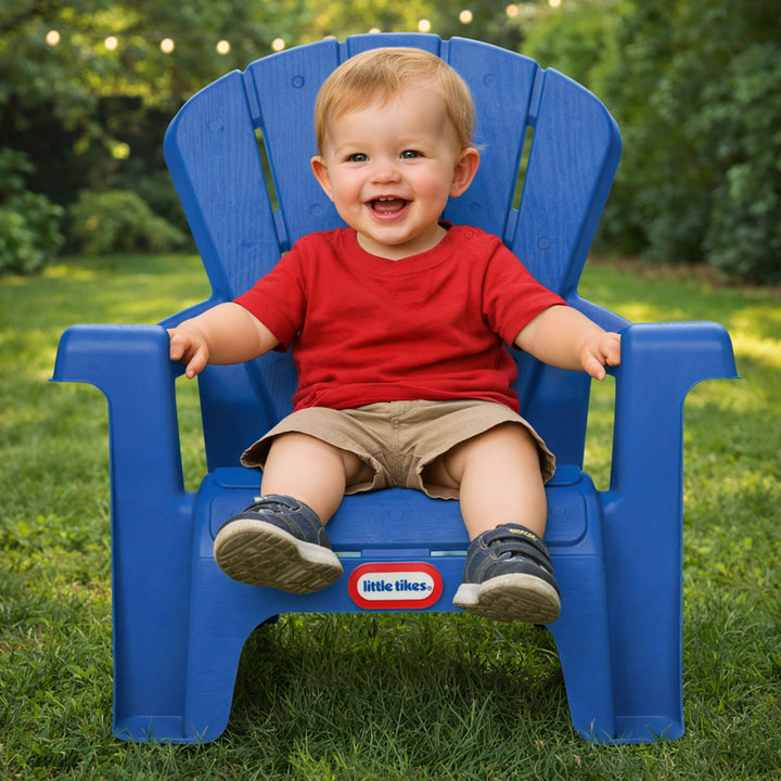 Child sitting on a blue chair with 'Little Tikes' branding in a garden setting