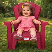 Child in a pink dress sitting on a red chair with 'Little Tikes' logo outdoors.