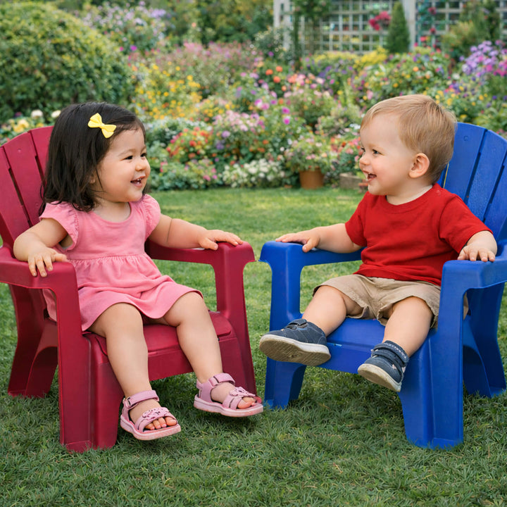 Two children sitting on red and blue chairs in a garden