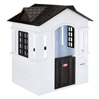 A white plastic playhouse with a black tiled roof and a black door and mail slot, shown on a plain white background.