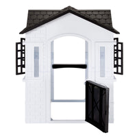 A white plastic playhouse with a black tiled roof and a black door and black window shutters, shown on a plain white background.