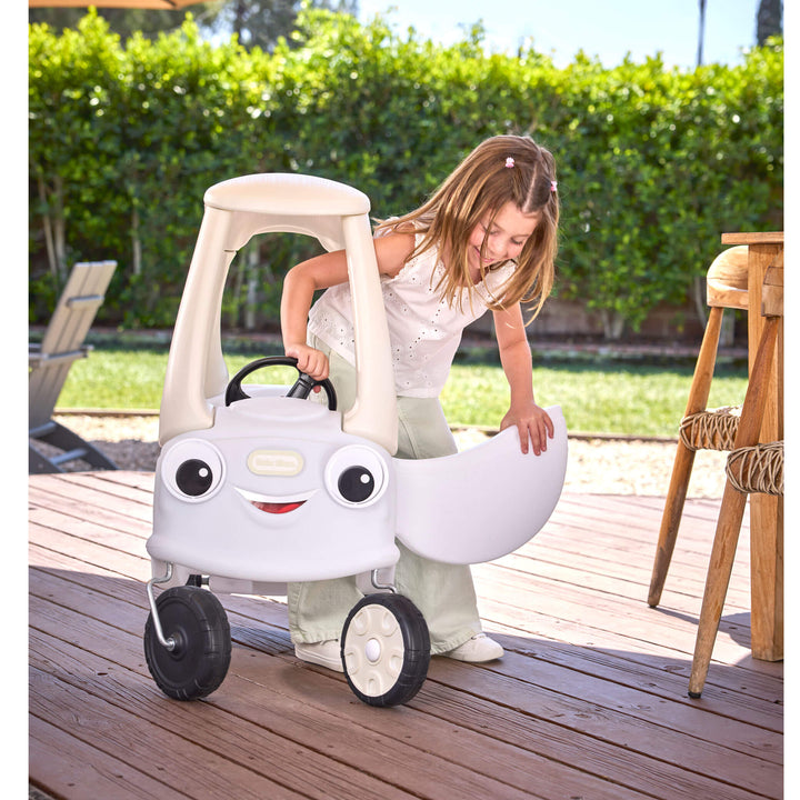 Child opening the door of the coupe car on a brown wood deck