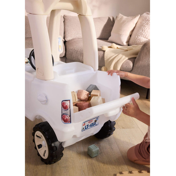 truck bed open with blocks inside, little hands on drop down tailgate on hardwood floor with a couch in the background