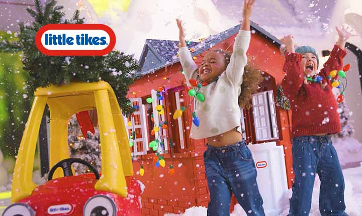 Children playing in front of a Little Tikes playhouse with snow and Christmas lights.