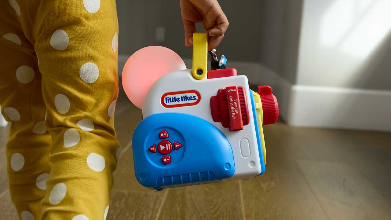 Child holding a Story Dream Machine with polka dot pants in the background